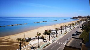 A coastal road with a beach and a cityscape in the background.