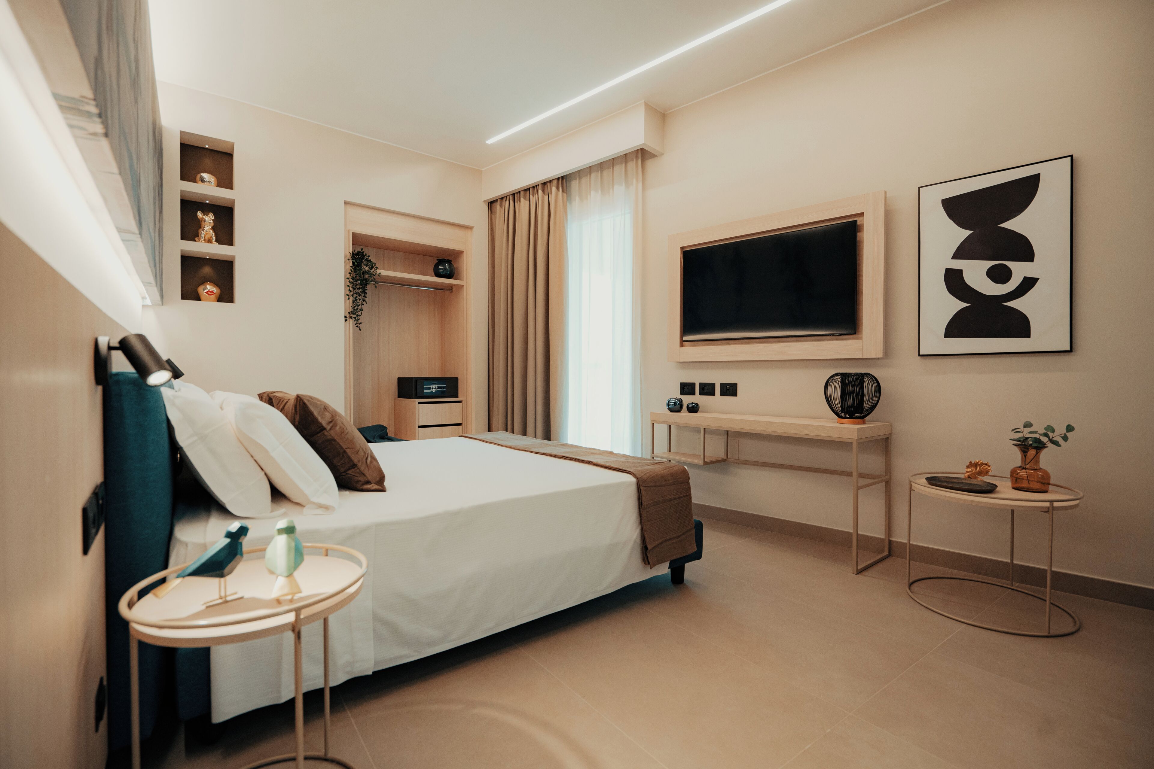 Una habitación de hotel moderna con cama, mesita de noche, televisor y escritorio con silla.