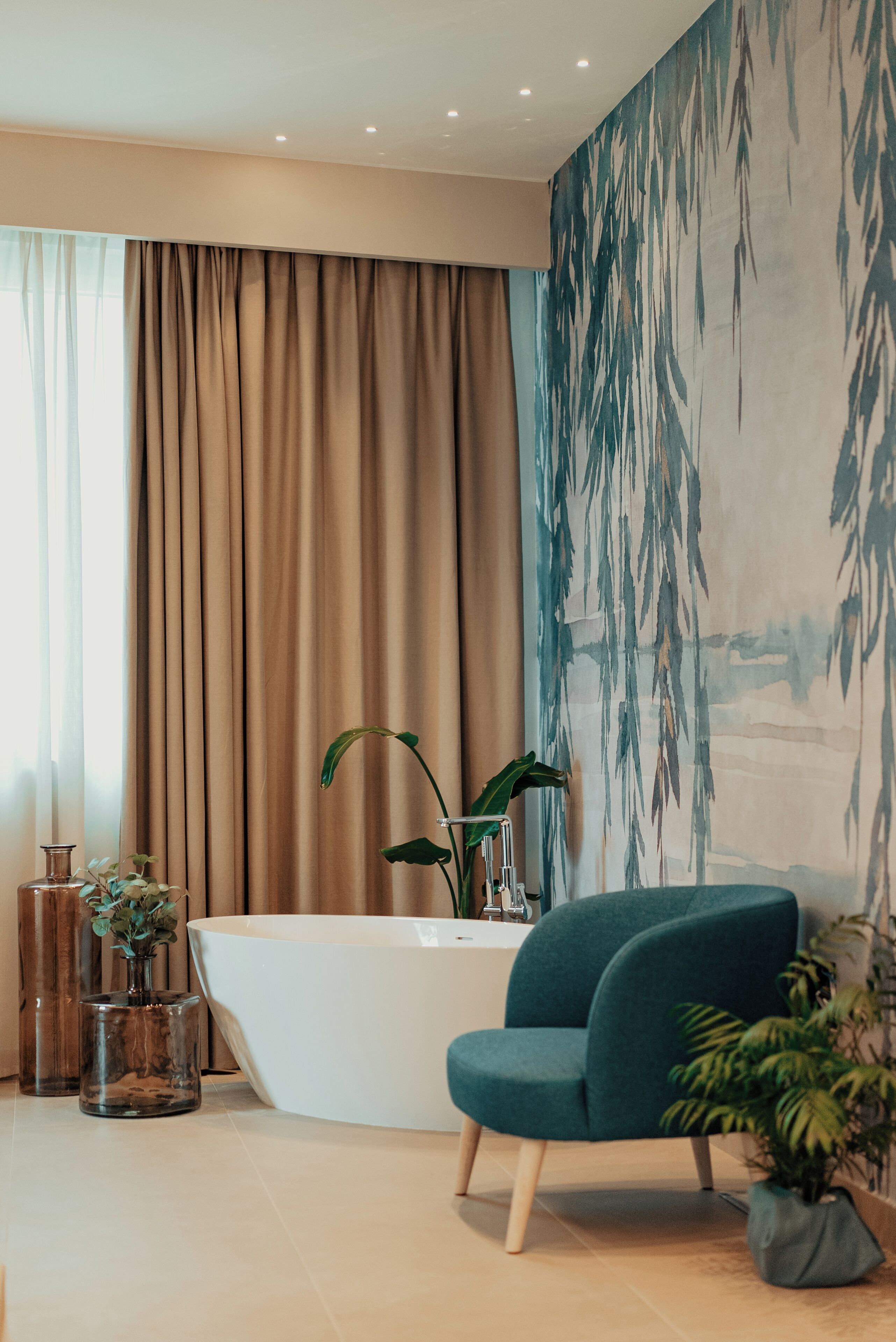 Un baño moderno con una bañera independiente, un sillón color aguamarina y un mural grande en la pared.