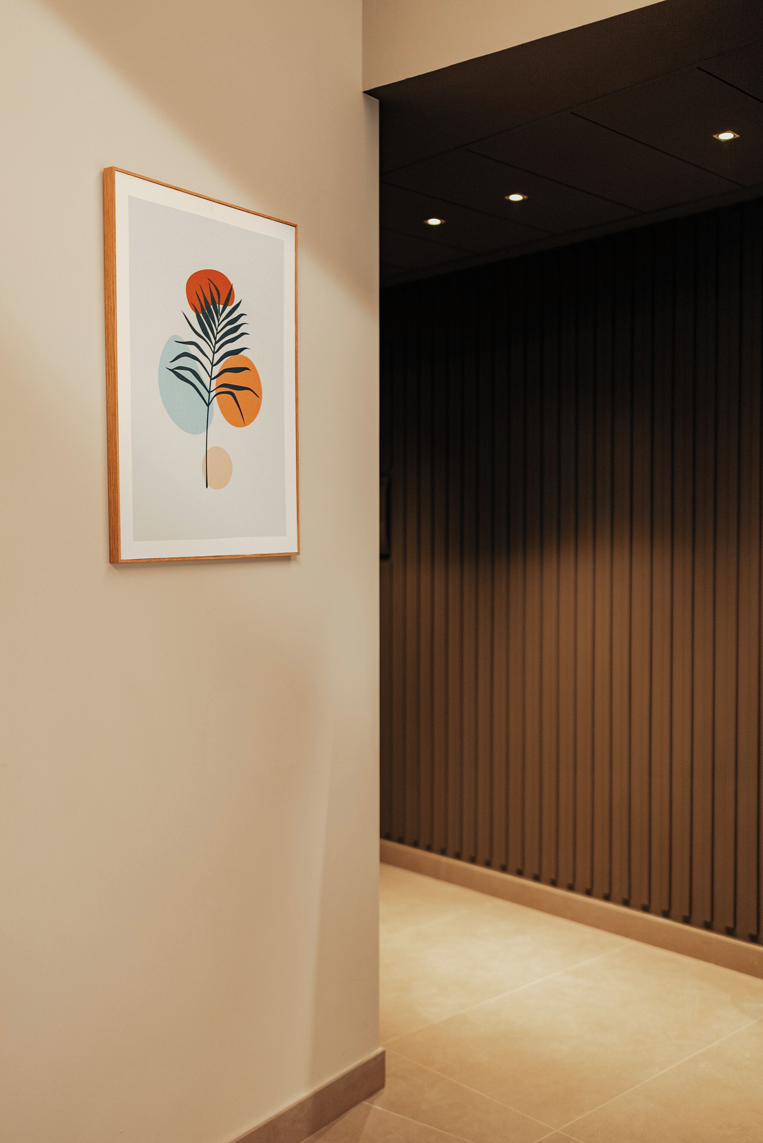 A framed artwork on a wall in a hallway with a wooden panel wall and a tiled floor.