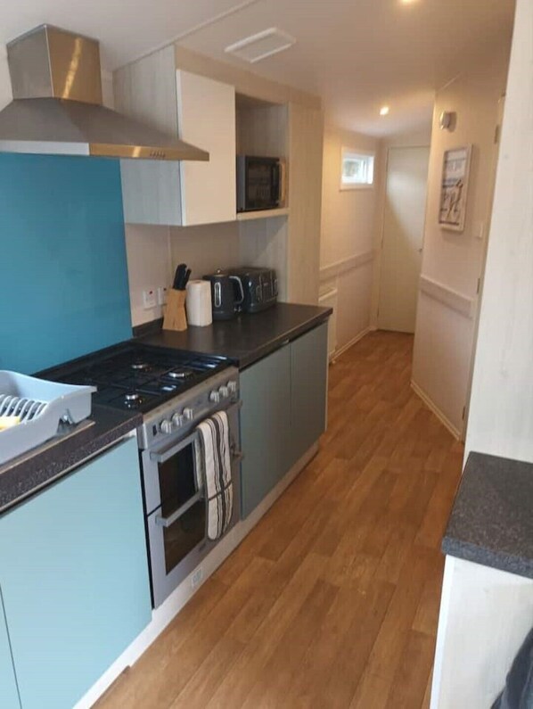 A compact kitchen with a stove, oven, microwave, and a small countertop. - The Montgomery Moonstone, Middlemuir Holiday Park, (Tarbolton)