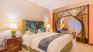Habitación de hotel con una cama grande, dos lámparas de noche, un cabecero decorativo, una mesita y una silla.