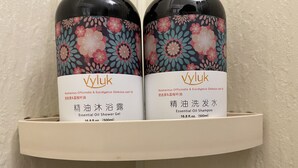 Dos botellas de champú esencial de Vyluk sobre una estantería.
