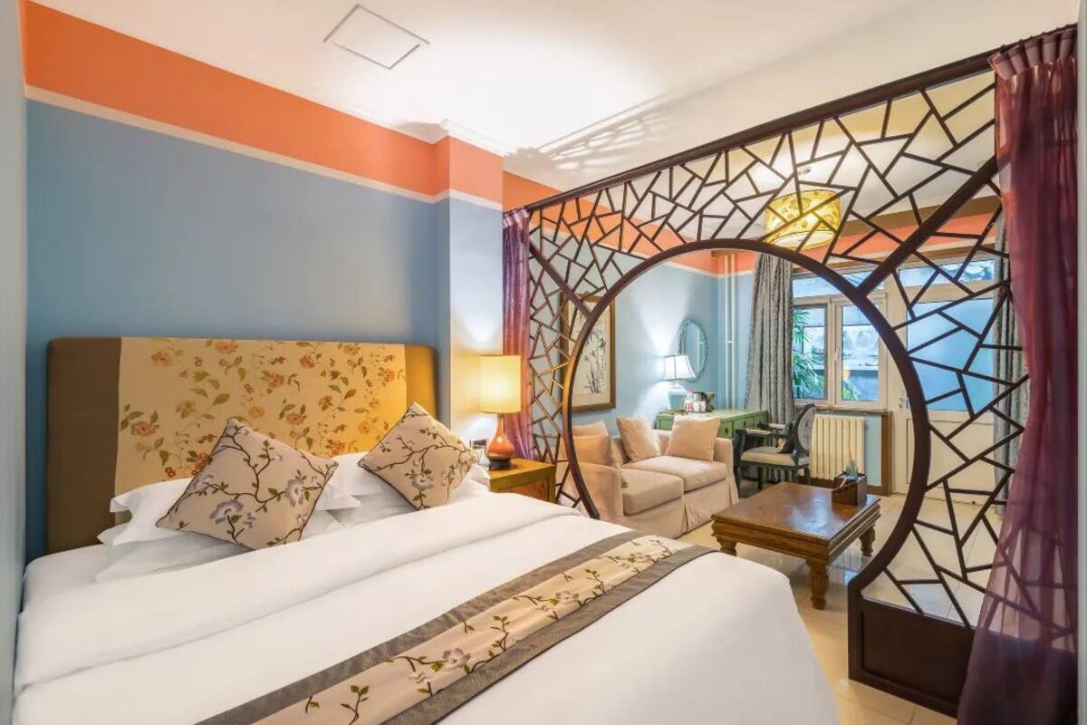A hotel room with a bed, a desk, a chair, and a view of the outside.