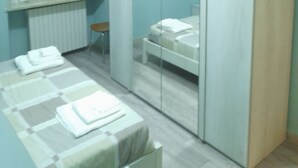 Une chambre à coucher comprenant un lit, une table de chevet, une chaise, une armoire et une fenêtre avec des stores.