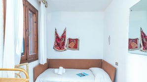 A room with a bed, a chair, and a window with curtains. - Laldiola (Olbia)