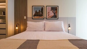 A neatly made bed with a patterned throw, two framed pictures on the wall, and bedside lamps. - w* | Marvelous 2BR with balcony in Miraflores (Lima)