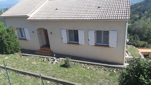 Une maison à deux étages, avec un toit en tuiles, une porte d’entrée et un petit porche.