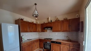 Une cuisine de taille réduite, dotée de meubles en bois, d’un réfrigérateur blanc, d’une cuisinière et d’un lave-vaisselle.