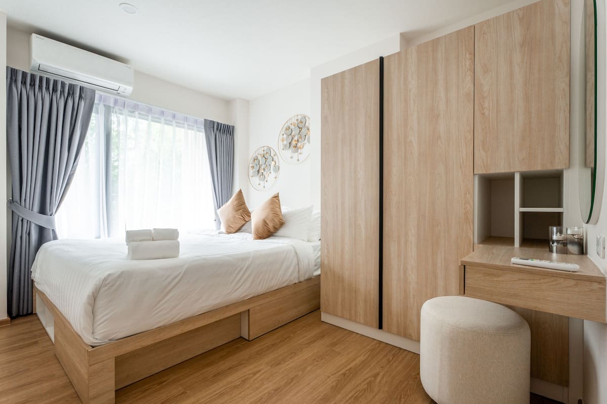 A modern bedroom with a wooden bed, a desk, and a wardrobe.