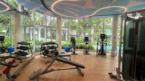A modern gym with various exercise equipment, large windows, and a wooden floor. - Phyll Phuket by NLA (Wichit)