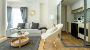 A modern living room with a sofa, a round coffee table, and a chair. - Phyll Phuket by NLA (Wichit)