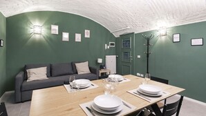 A dining area with a wooden table set for four, a sofa, and a coat rack. - Easylife - Elegance in the Isola district (Milano)