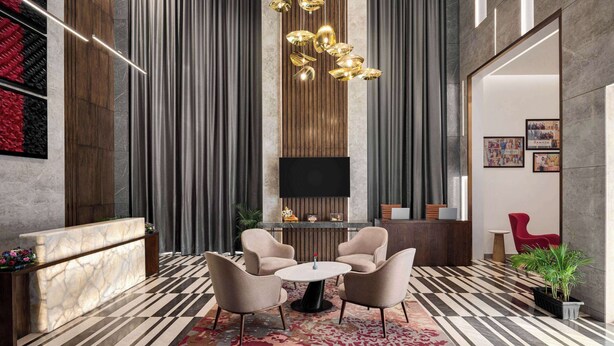 A modern lobby with a reception desk, seating area, and a large TV screen.
