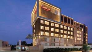A modern hotel building with a prominent sign reading "RAMADA BY WYNDHAM."