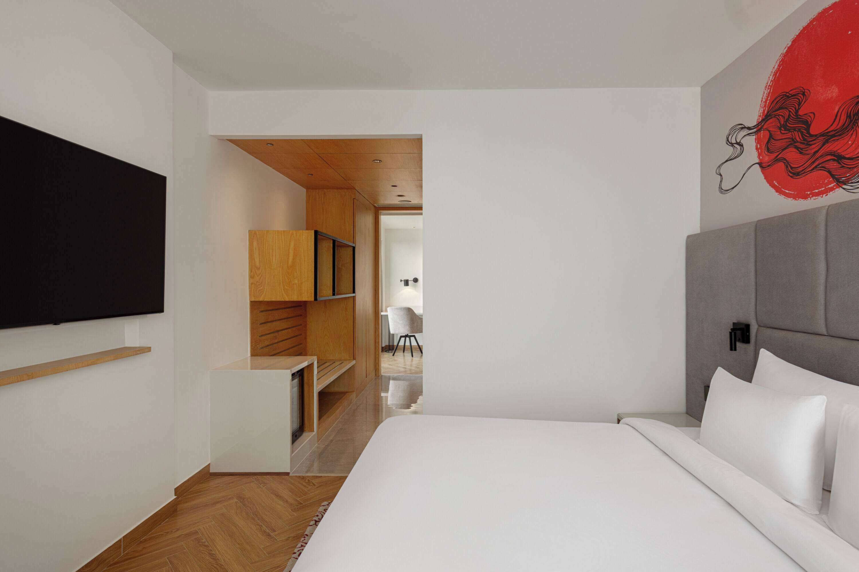 Quarto moderno com uma cama grande, estantes de madeira e um quadro abstrato vermelho na parede.
