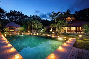 A swimming pool with candles around the edge, surrounded by lush greenery and a gazebo. - Breathtaking Pool Villa With Mountain View! (Bali)