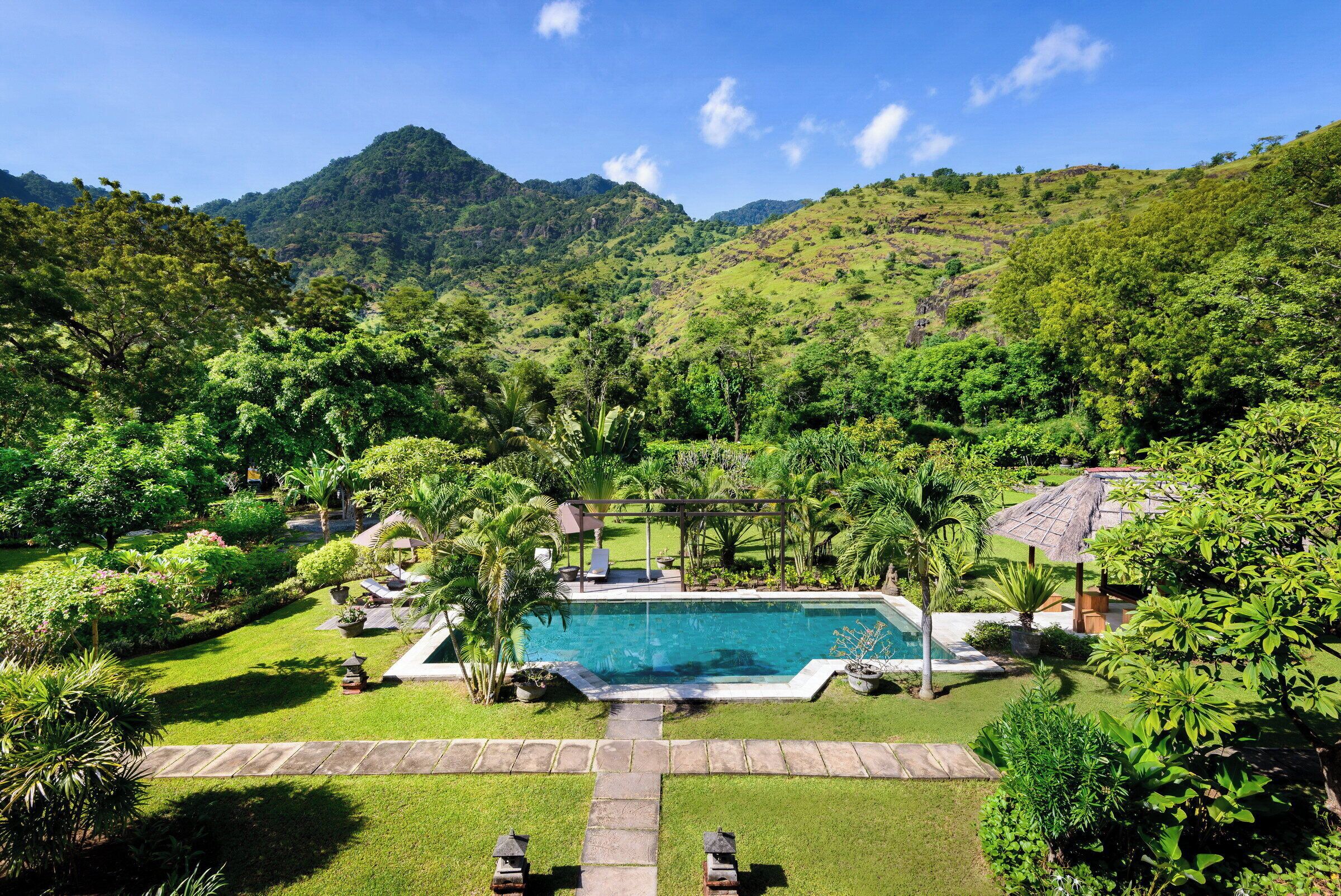 A swimming pool surrounded by lush greenery and hills.