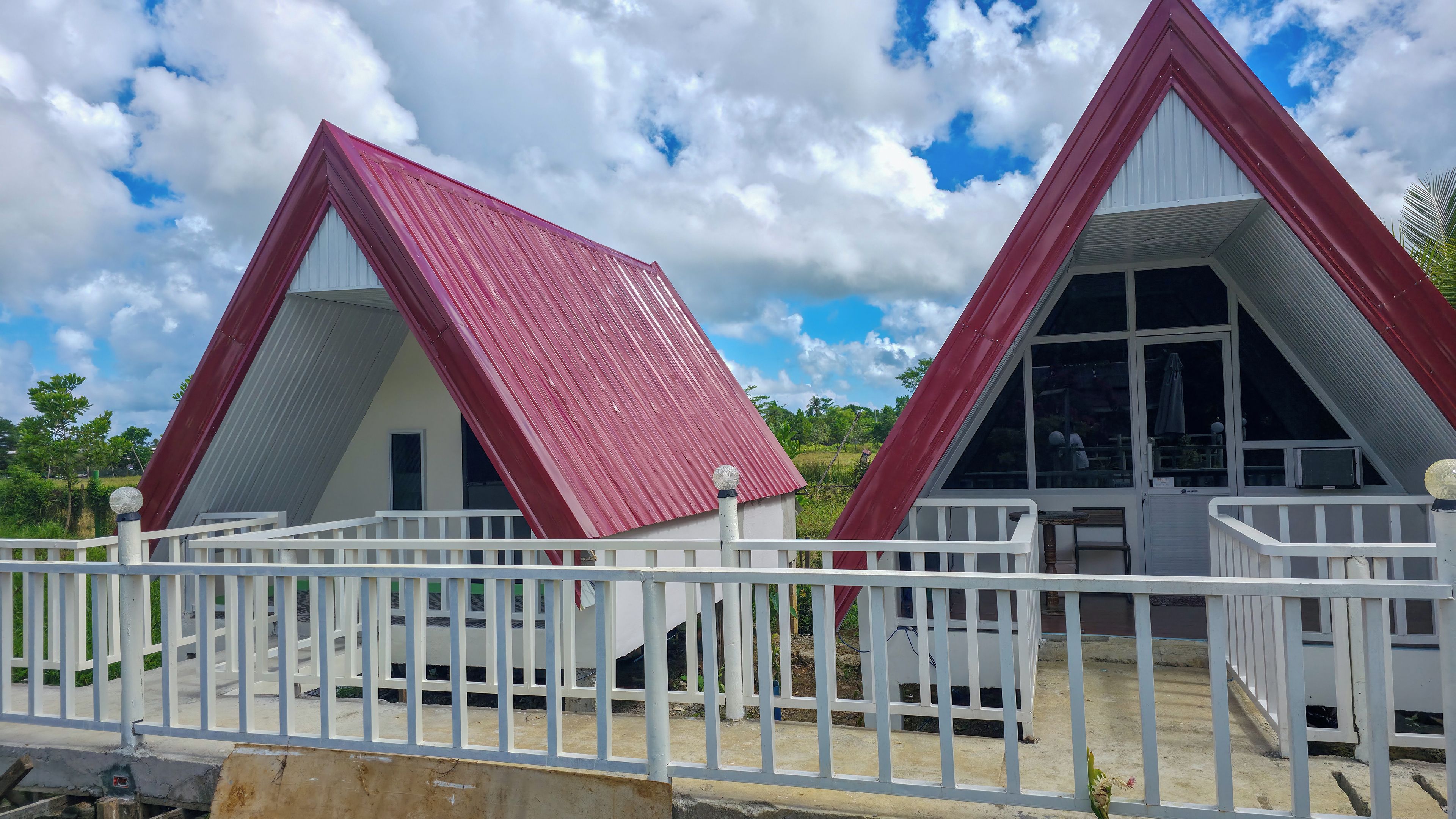 Two triangular buildings with red roofs, white railings, and a clear sky.