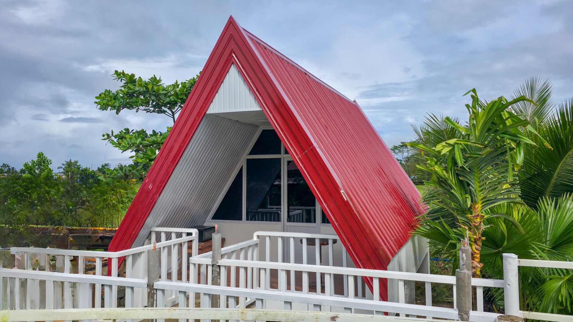 A red, triangular-shaped building with a white railing in front.