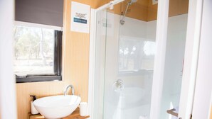 A bathroom with a white sink, a glass shower enclosure, and a window.