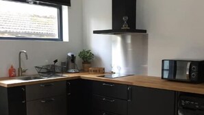 A modern kitchen with a black dishwasher, a microwave, and a sink. - Studio Moderne (Saint-Symphorien-d'Ozon)