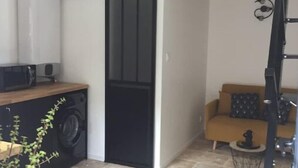 A compact living space with a loft bed, a washing machine, a sofa, and a ladder. - Studio Moderne (Saint-Symphorien-d'Ozon)