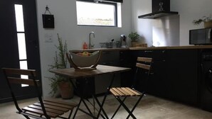 A compact kitchen with a dining area, a window, and a microwave. - Studio Moderne (Saint-Symphorien-d'Ozon)