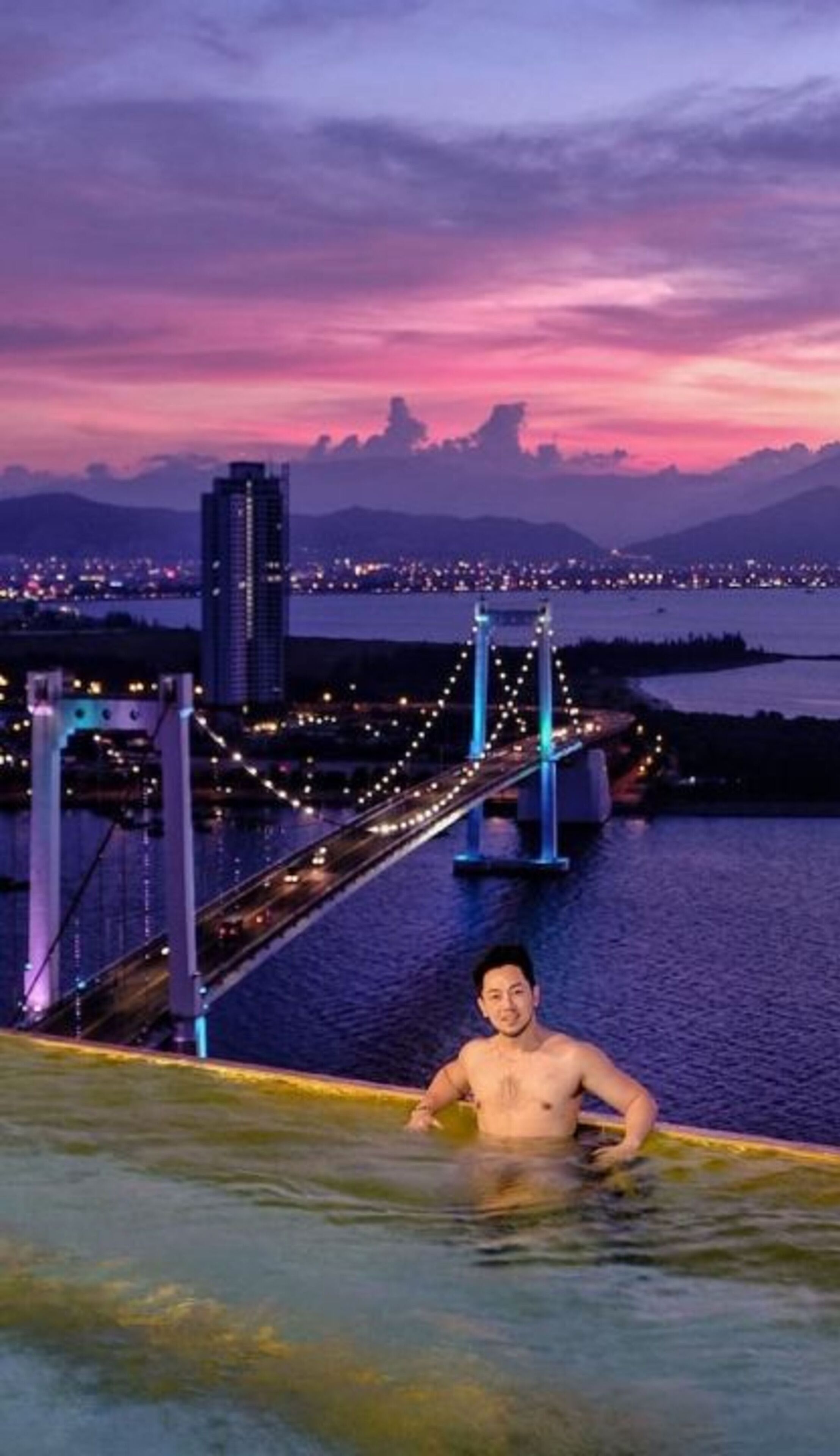 A person in a pool with a bridge and cityscape in the background.