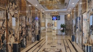 A modern hotel lobby with marble walls, a decorative floor pattern, and a central chandelier. - Dana Pearl Bay Apartment by Dimo Trip (Da Nang)