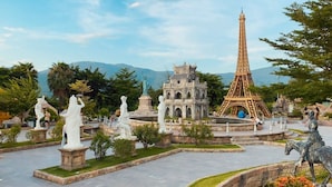 A park with statues, a replica of the Eiffel Tower, and a building resembling a temple. - Dana Pearl Bay Apartment by Dimo Trip (Da Nang)