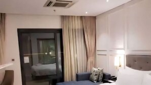 A hotel room with a large bed, a desk, a chair, and a sliding glass door to a balcony. - Dana Pearl Bay Apartment by Dimo Trip (Da Nang)