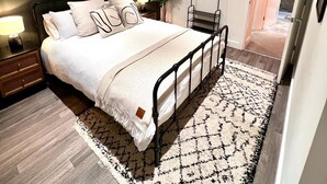 Quarto moderno com cama, mesas de cabeceira, uma cadeira suspensa e obras de arte na parede.