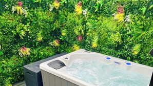 Uma banheira de hidromassagem com degraus, rodeada por vegetação exuberante.