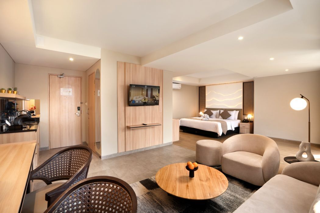 Una habitación de hotel moderna con zona de comedor, televisor, cama y sofá.