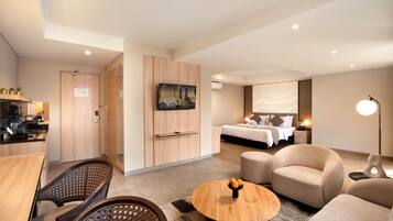 Una habitación de hotel moderna con zona de comedor, televisor, cama y sofá.