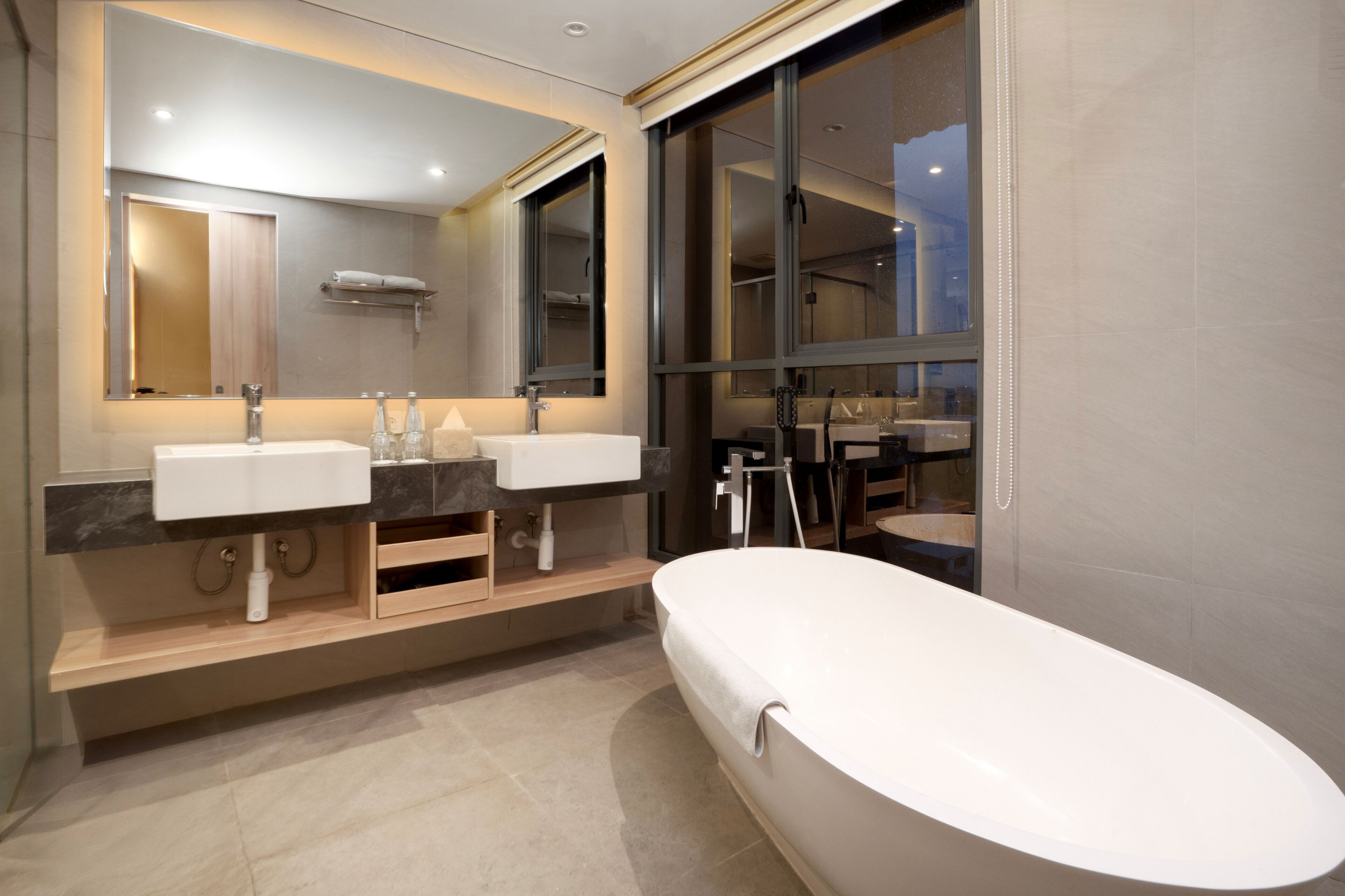 A modern bathroom with two sinks, a large bathtub, and a large mirror.