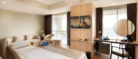 A modern hotel room with a large bed, a desk, a chair, a TV, and a mirror.