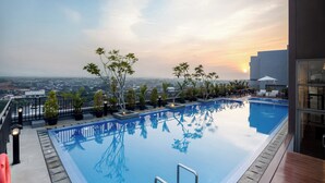 Una piscina en la azotea con vistas despejadas del paisaje urbano al atardecer.