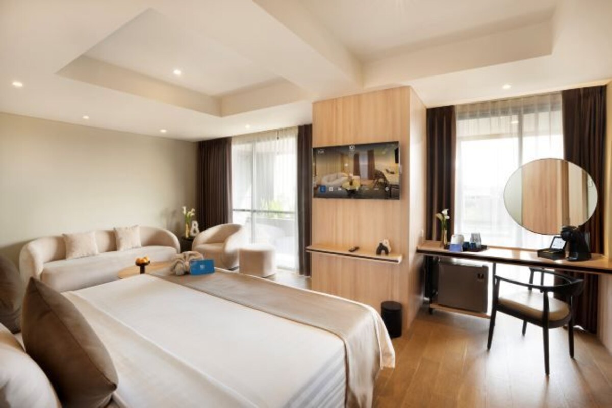 A modern hotel room with a large bed, a desk, a chair, and a large mirror.