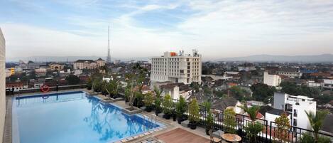 A rooftop swimming pool with a view of the cityscape, including a prominent building and surrounding residential areas.