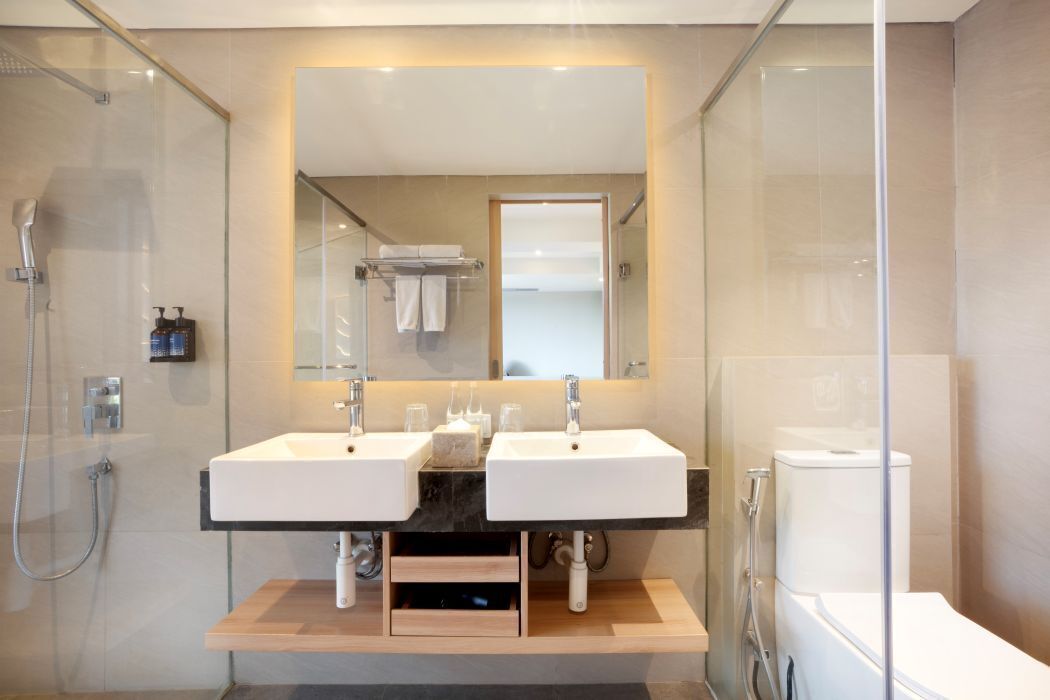 A modern bathroom with two sinks, a glass shower enclosure, and a toilet.