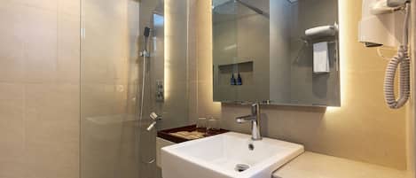 A modern bathroom with a glass-enclosed shower, a white sink, and a hairdryer mounted on the wall.