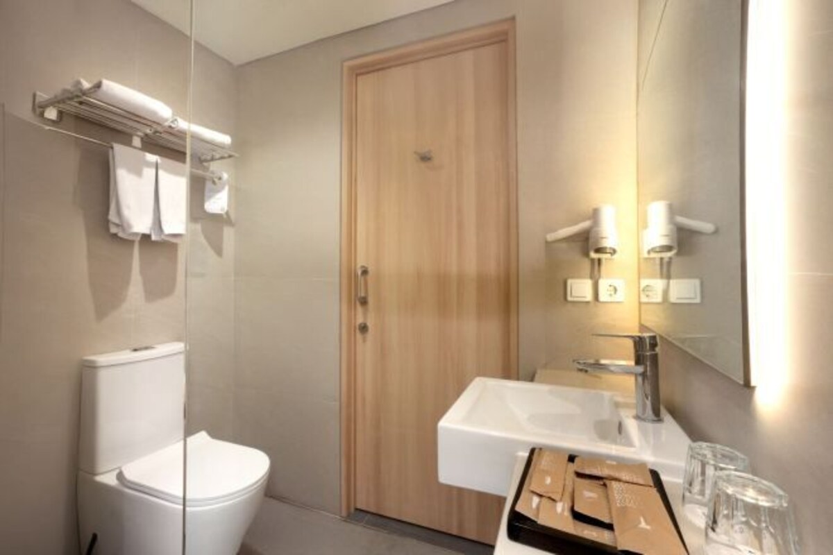 A modern bathroom with a toilet, a sink, and a mirror.