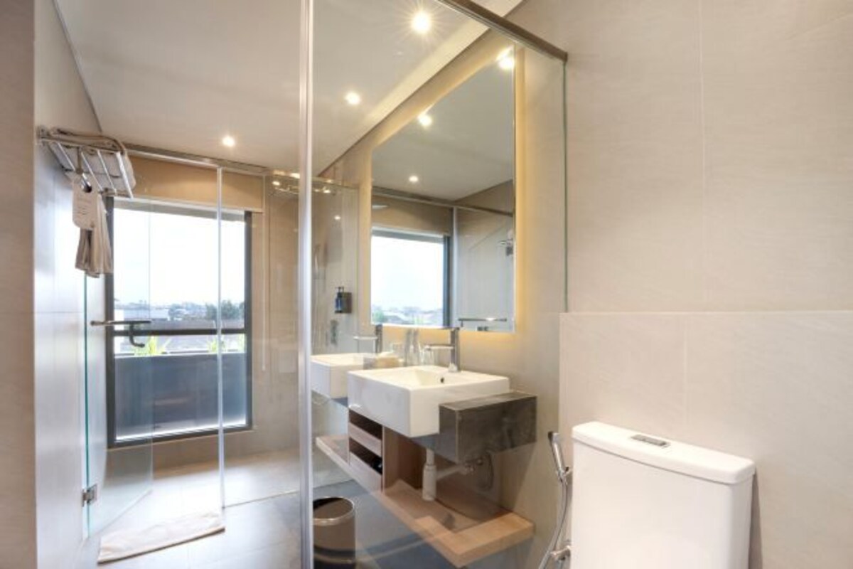 A modern bathroom with a glass shower enclosure, dual sinks, and a large mirror.
