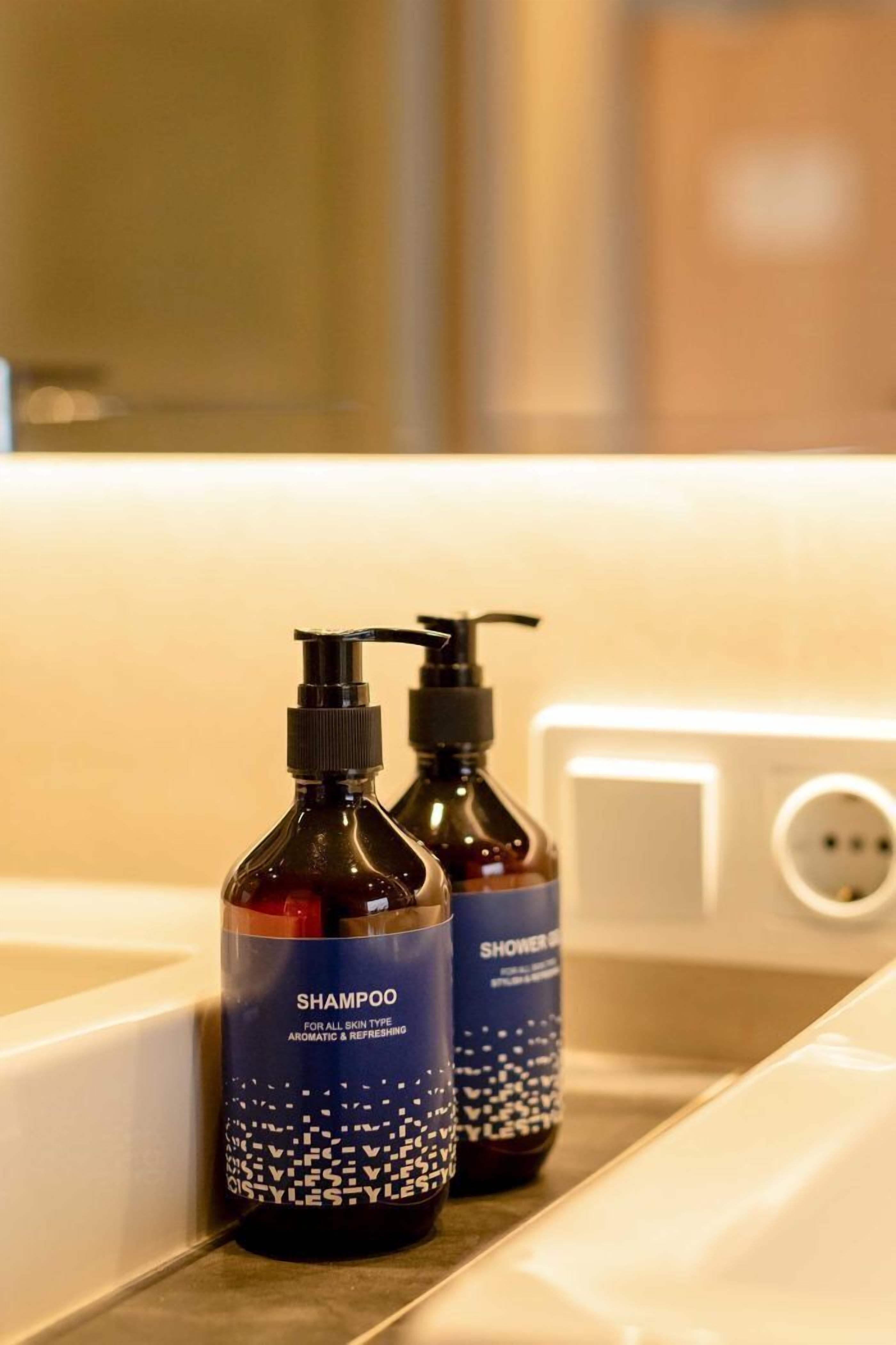 Two bottles of shampoo and a shower gel on a bathroom counter.