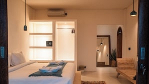 Un dormitorio con cama, mesitas de noche, armario y una pequeña zona de estar con un banco.