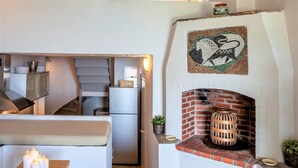 Ein modernes Interieur mit Kamin, Steinböden und einer Sitzecke mit Tisch und Kerzen.