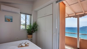 Ein Schlafzimmer mit einem Bett, einer Topfpflanze, einem Fenster und Blick auf das Meer.