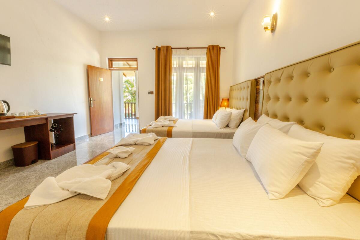 Quarto de hotel com duas camas, uma mesa e vista para o exterior.